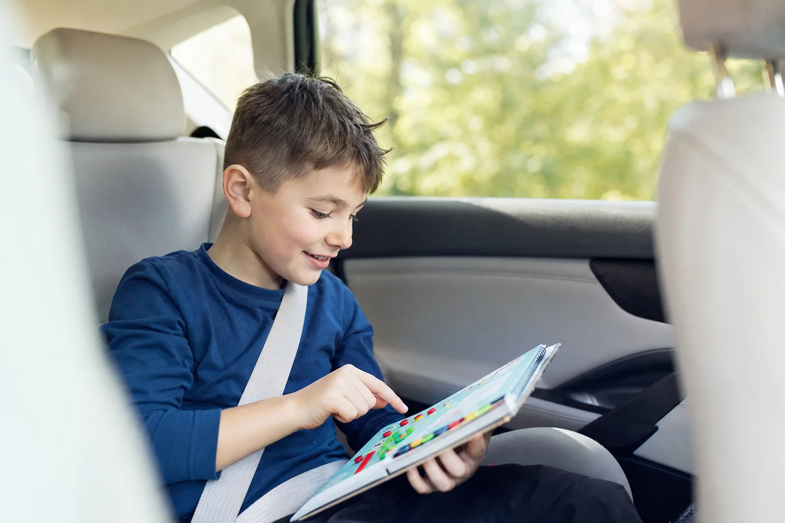 Kind spielt vergnügt mit einem Reisespiel im Auto