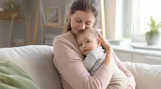 Mutter hält ihr Baby beschützend und geborgen im Arm