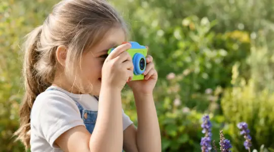 Fröhliches Kind fotografiert mit einer bunten Kinderkamera