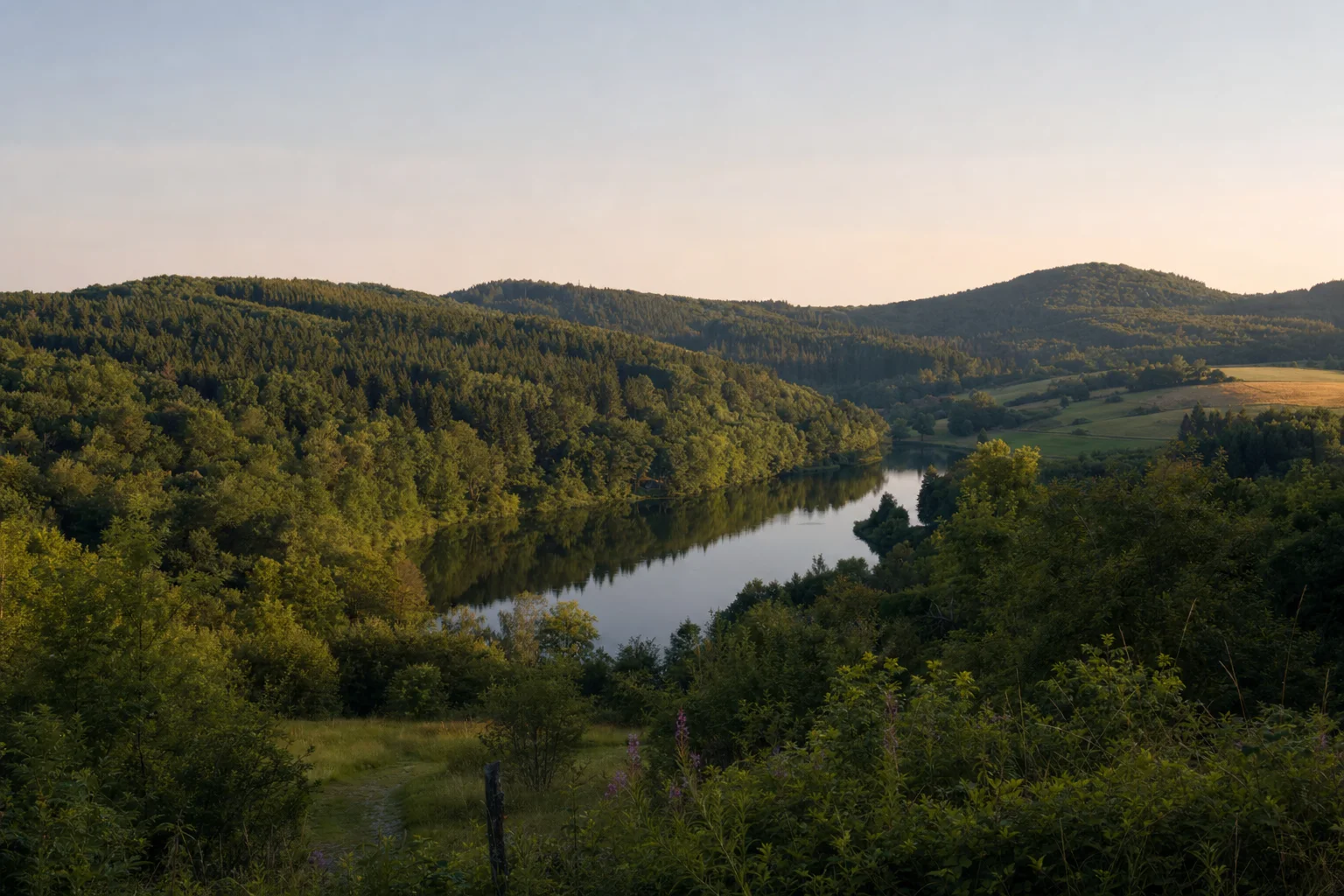 Grüne Hügellandschaft der Eifel mit See