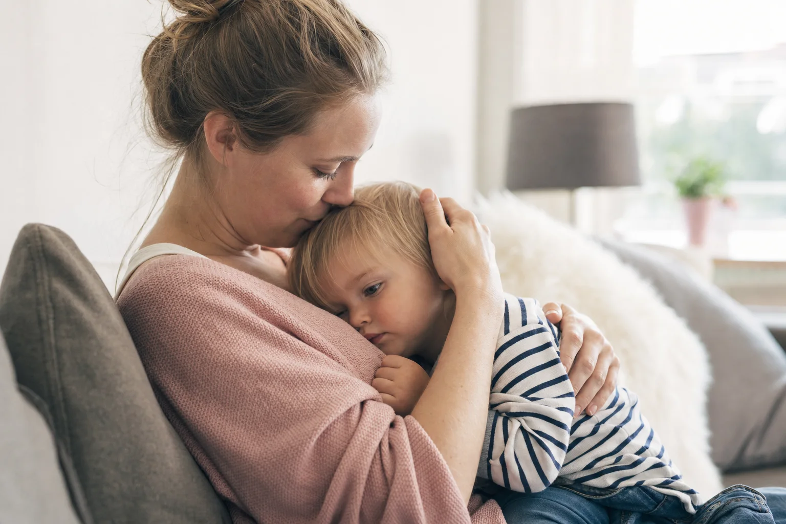 Mutter und Kind kuscheln liebevoll auf dem Sofa