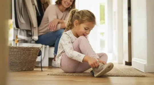 Kind zieht sich stolz selbst die Schuhe an