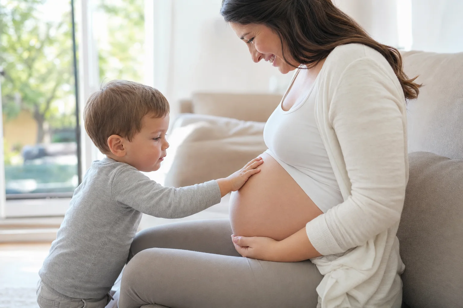 Kind legt sanft die Hand auf den Babybauch der Mutter